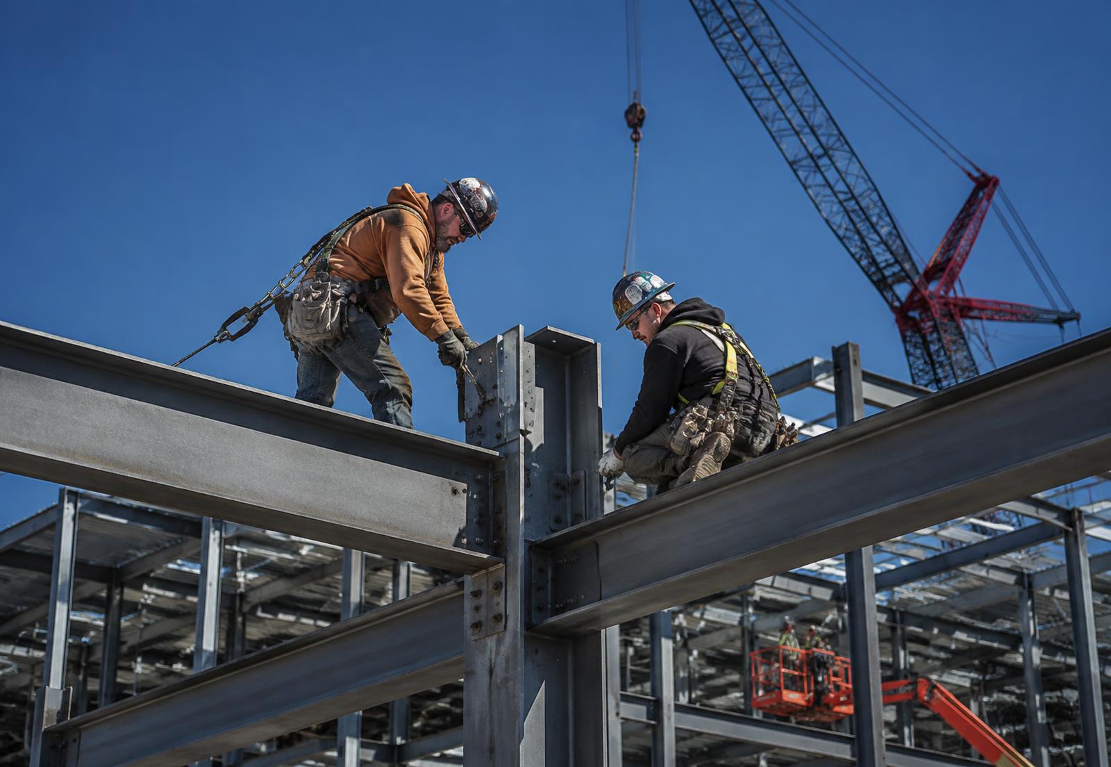 Crew erecting structural steel framing with lift equipment